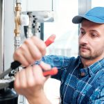 Contemporary young mechanic from household maintenance service repairing pipe