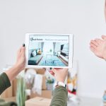 Young woman holding touchpad with advertisement of new real estate on screen